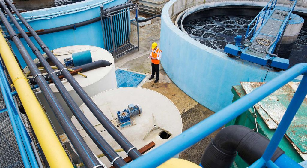 Water utility worker stands among tanks