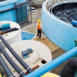 Water utility worker stands among tanks